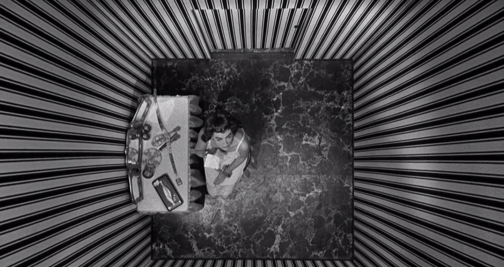 Plan en plongée vu du dessus carrément, Joan Crawford enfermé dans une petite salle, les murs sont une alternance de lignes en noir et blanc
