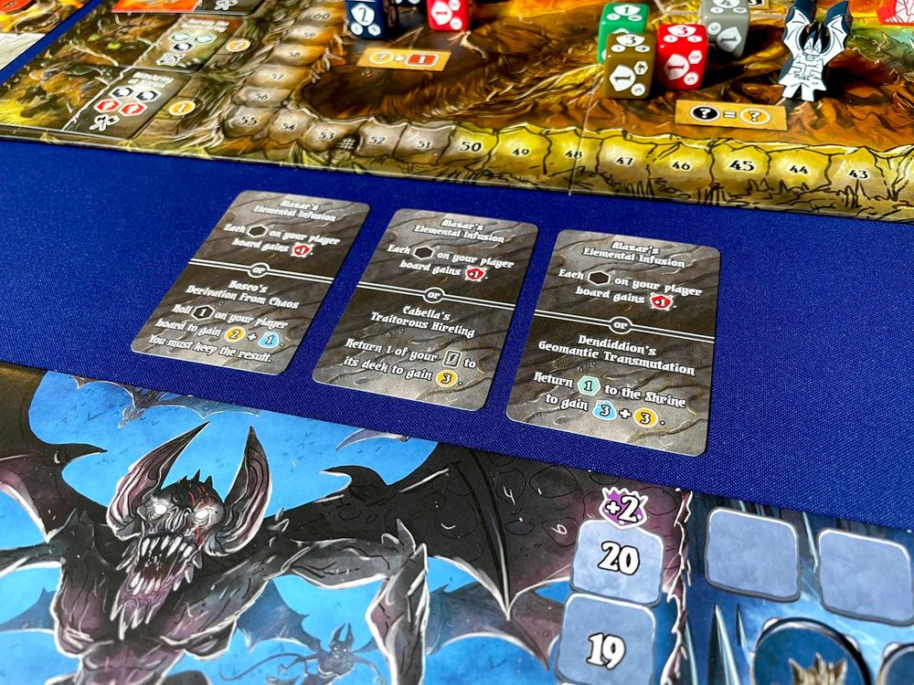 the board game Shadow Kingdoms of Valeria with three 'ancient spell' cards in front of one of the player boards.