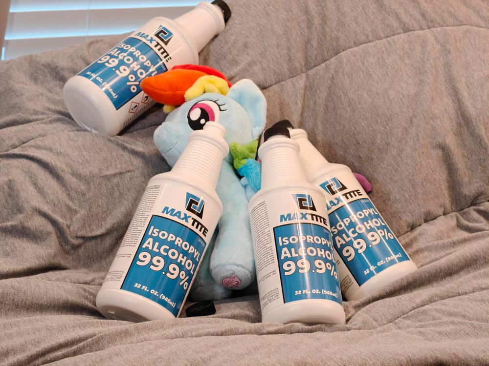 Rainbow Dash 4DE plushie lying on a bed surrounded by containers of isopropyl alcohol.