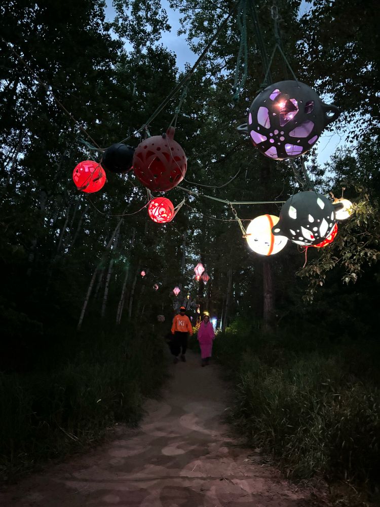 A dark pathway lit with artfully carved buoys and lanterns.,