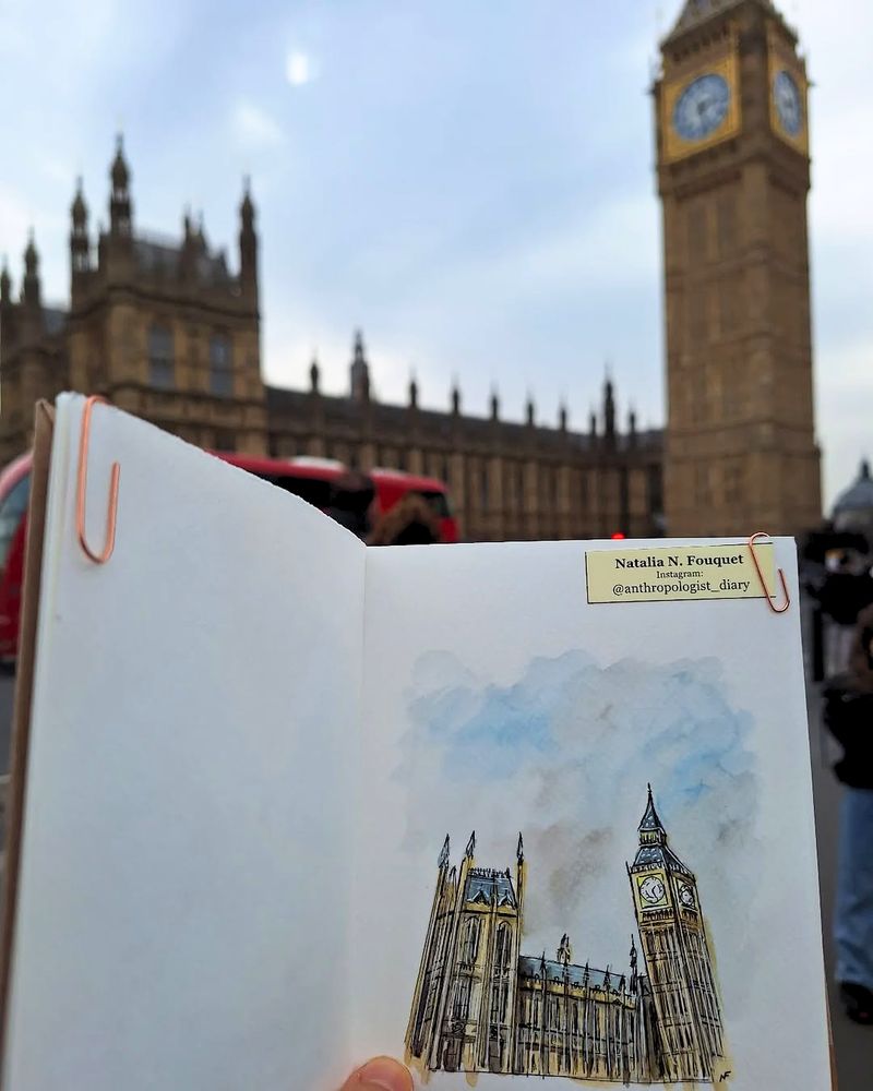 A watercolor and ink painting of Elizabeth Tower, held in front of the actual Elizabeth Tower in the background. 