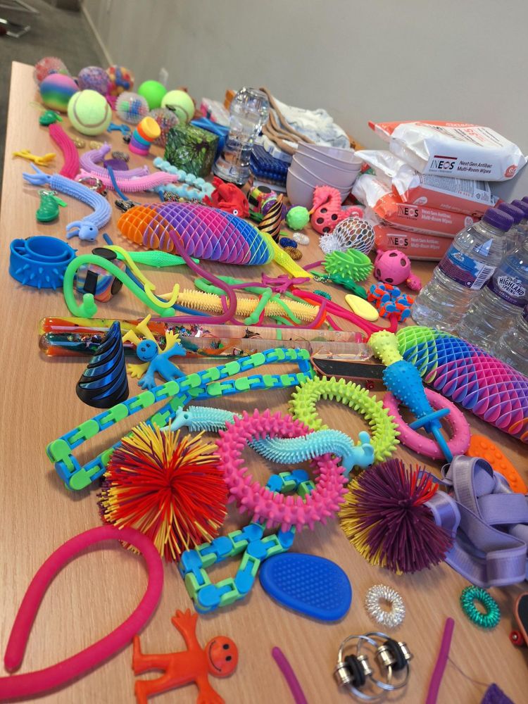 A table filled with colourful plastic sensory toys, including balls and puzzles