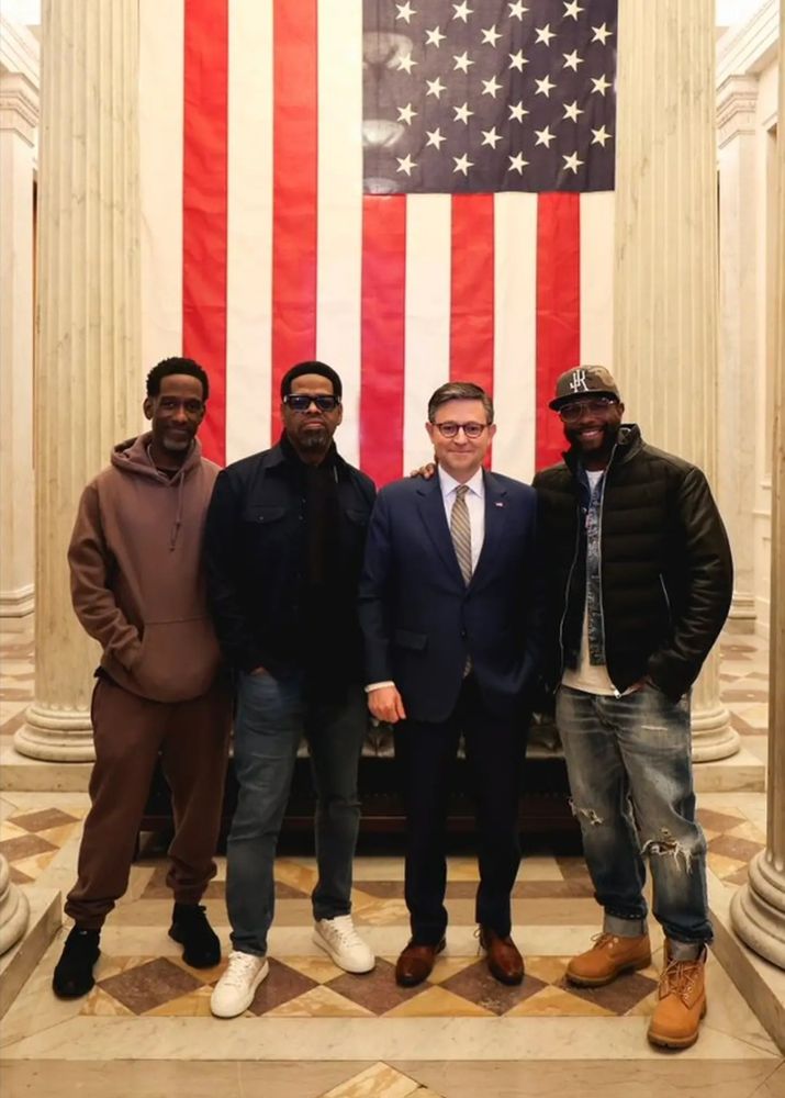 Boyz II Men posing with Speaker Mike Johnson in front of a 20ft vertically draper US flag
