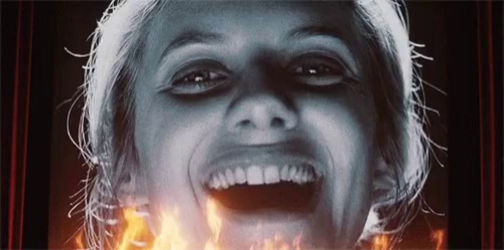 a close up of a woman 's face with fire behind her mouth