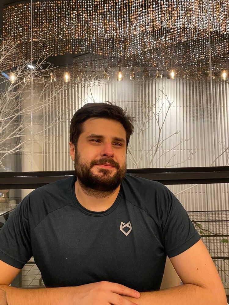 Foro de Anderson sorrindo. Ele tem cabelos, olhos e barba castanha.