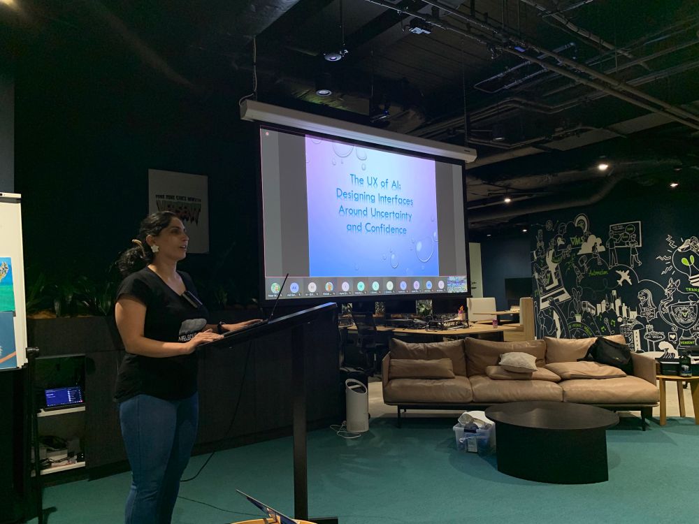 Maryam Yasaei stands next to her presentation slide titled "The UX of AI: Designing Interfaces around Uncertainty and Confidence"