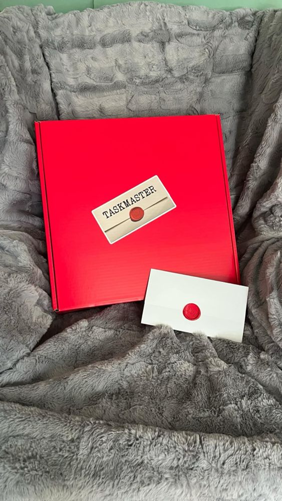 A large red box with a taskmaster envelope. 
