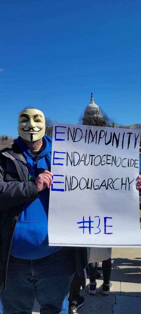 Me holding a sign in front of the Capitol saying "End impunity. End autogenocide. End oligarchy. #3e