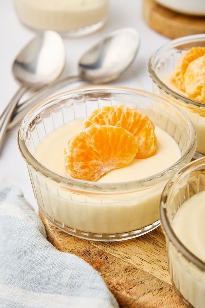 Ricotta mousse topped with two mandarin slices and served in a clear glass ramekin