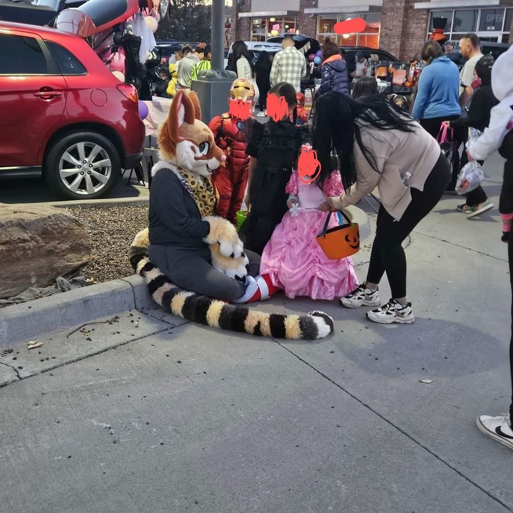 me sitting on the curb of a trunk or treat event saying hello to kids