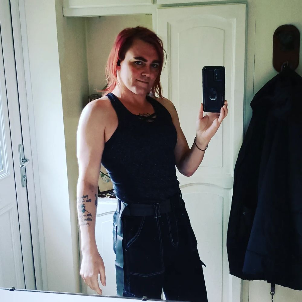 Same fit as the last pic, but facing the other way, so my face is in shadow. My left arm is hanging loosely down, backlit by the window