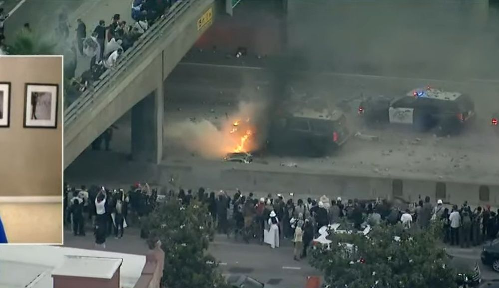 Demonstrators watch as a police car burns on a highway in downtown Los Angeles on June 8, 2025.