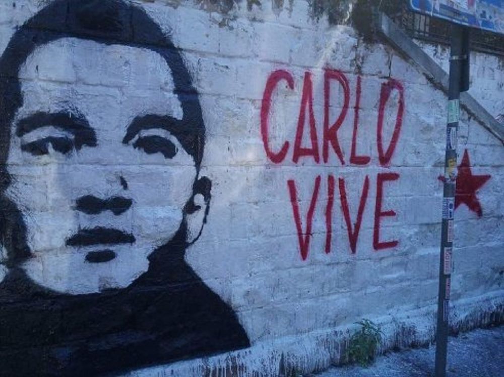 Graffiti remembering Carlo Giuliani, reading "Carlo Vive" with an image of his face.