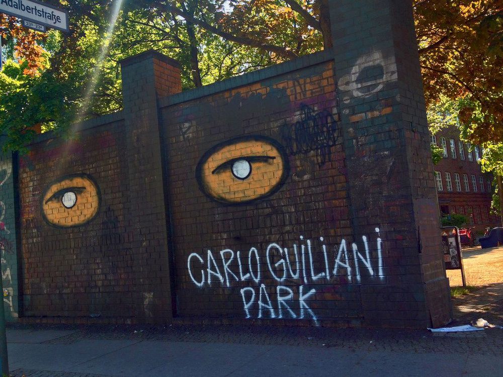 A photograph of a wall painted to read "Carlo Giuliani Park" in Berlin.