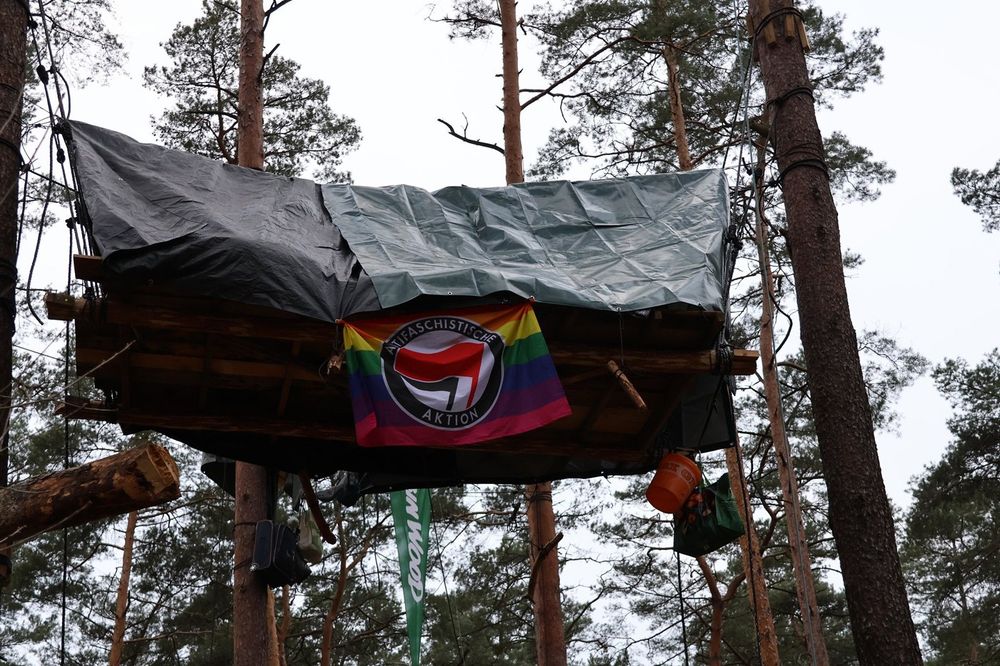 A tree house in the forest occupation outside the Gigafactory sports a rainbow-colored anti-fascist action flag.