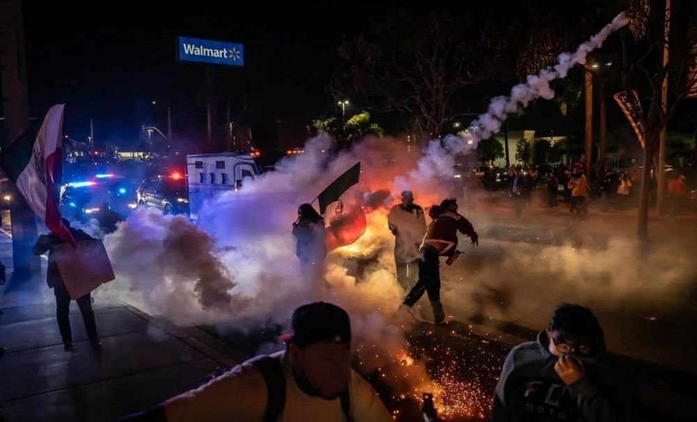 Demonstrators in San Diego throw back tear gas as riot police attack them.