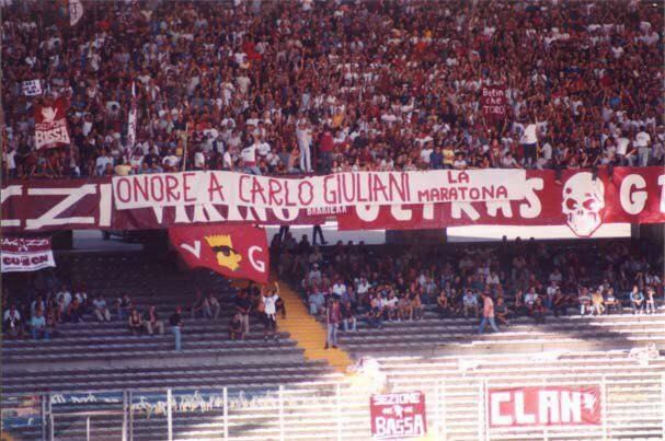 A photograph from 2001 showing he terrace of the hardcore supporters of Turin F.C., Ultras Granata, displaying a banner reading "honor to Carlo Giuliani" over their own.