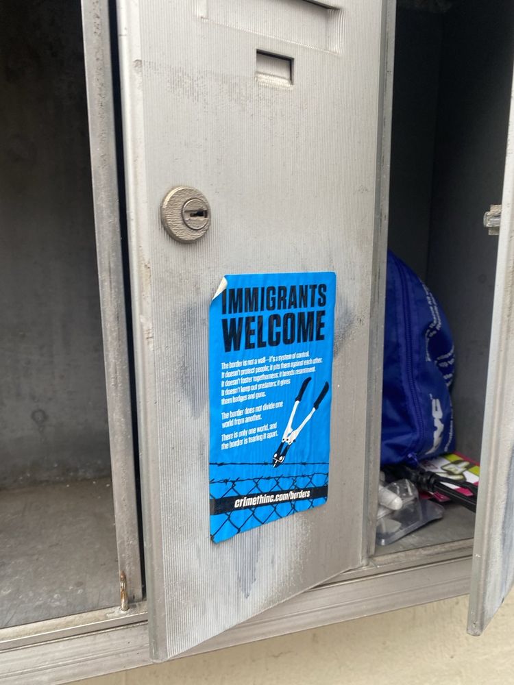 A sticker reading "Immigrants welcome" with an image of boltcutters cutting barbed wire on a mailbox.