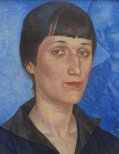 Oil portrait of Anna Akhmatova. She has fair skin, dark hair with short, blunt-cut bangs and the rest pulled back in a small braid or bun. Her face is rectangular, with light-blue eyes, a long, pronounced nose, and angular lips pressed tightly together. She is wearing a dark, collared dress or blouse. The background behind her is cornflower blue. There is an indistinct figure blending in with the background over her left shoulder. The figure appears to be a young person with a shaved head bowed in prayer.