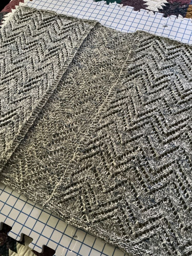 Lacy knitting project drying on a blocking mat.