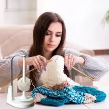 Woman poking knitting needles into a knit fabric in an unsuccessful attempt to portray a woman knitting