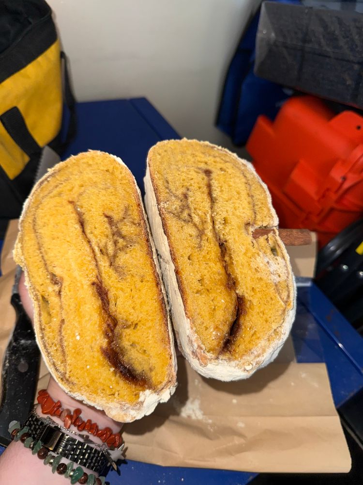 pumkin sourdough loaf sliced in half with cinnamon swirl going through the inside 