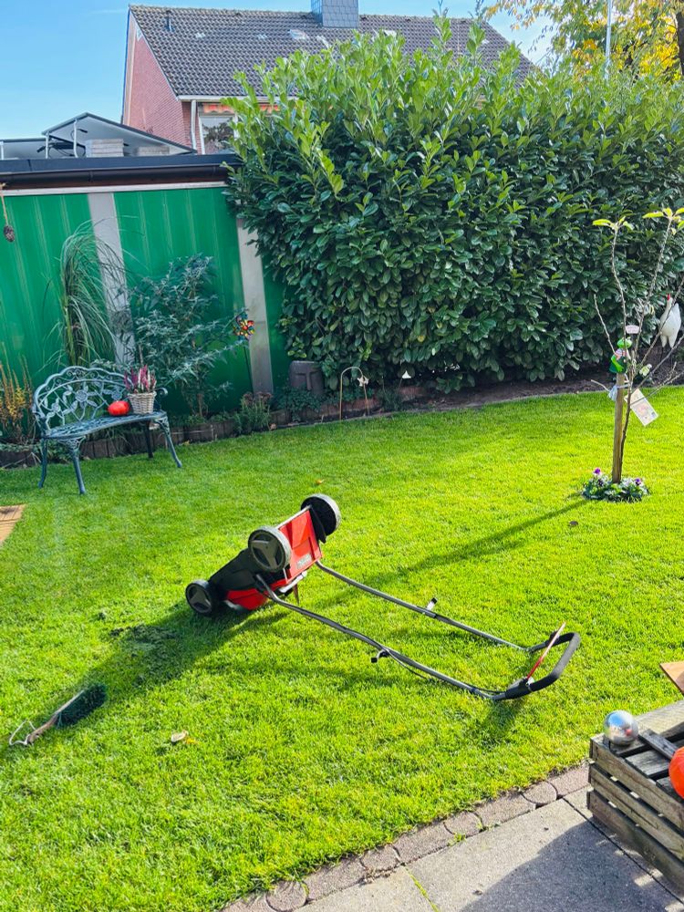 Der Rasenmäher liegt auf der Wiese.