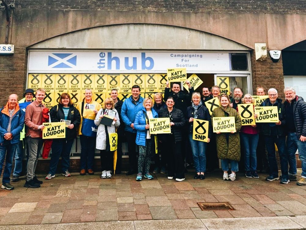 SNP activists standing holding placards outside the campaign hub in Hamilton.