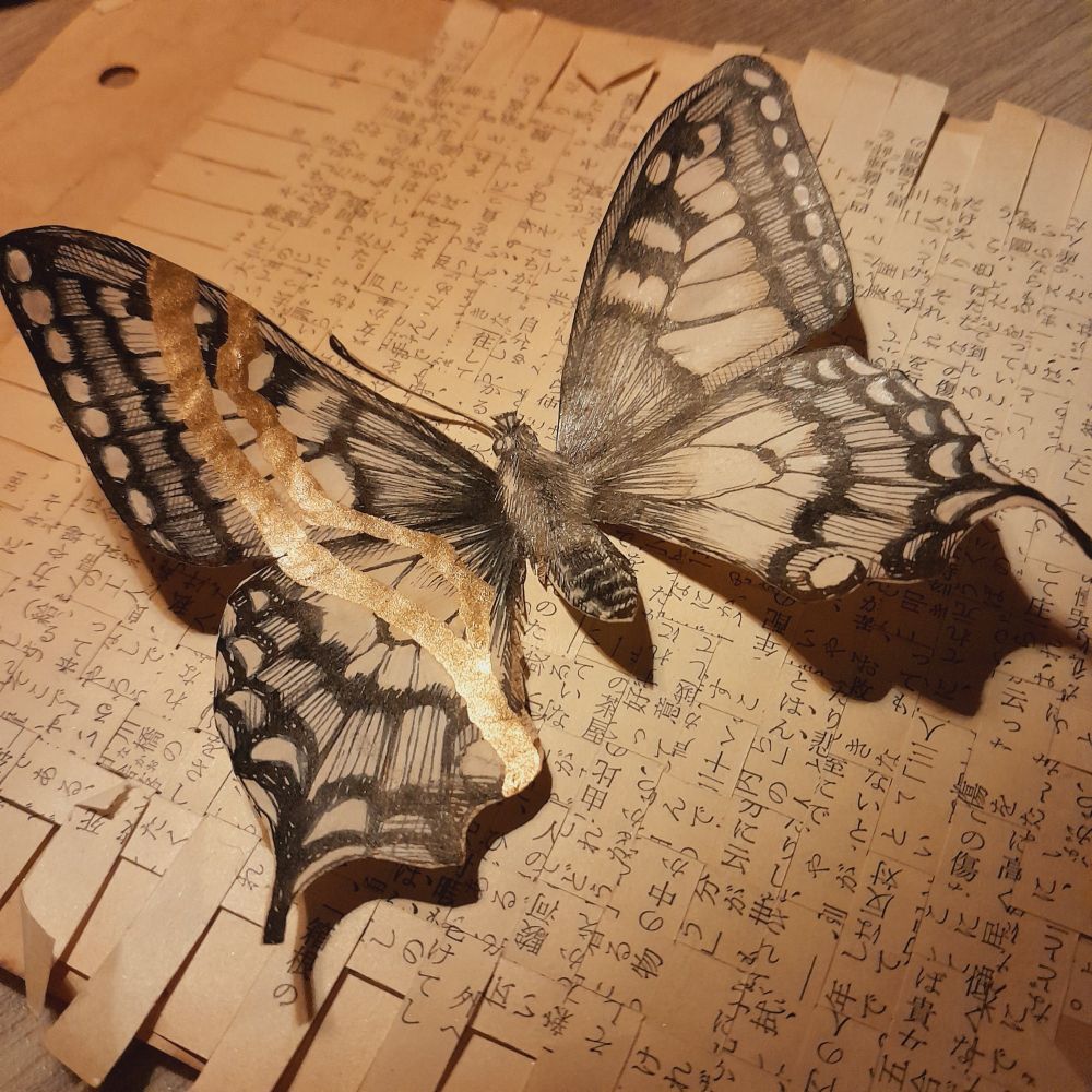 Papilio machaon illustration, outline cut out with X-acto, and lying lying on woven strips of paper.