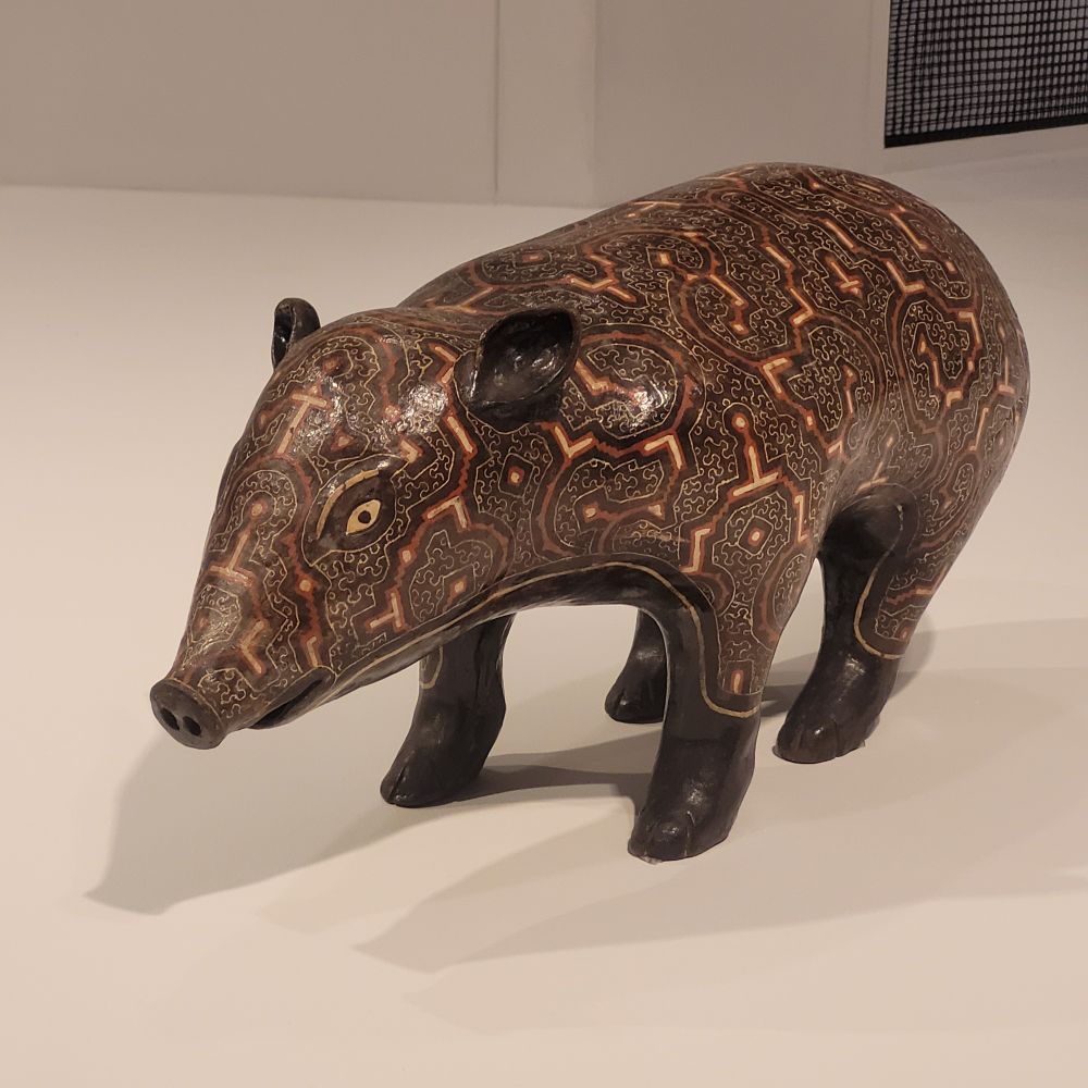 A sculpture of a pig who is dark brown with patterns.