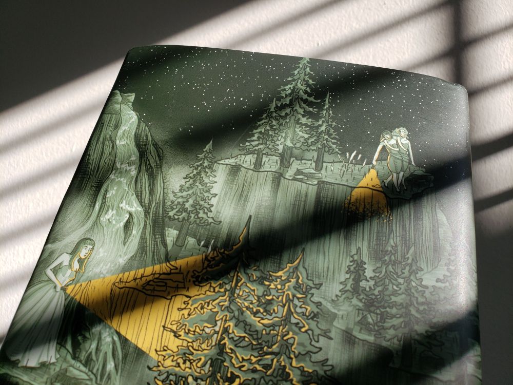 Photograph of part of the back cover of THE RESTLESS DARK Rainbow Crate special edition, showing a woman in a fancy dress looking through mountains as two drunk bridesmaids teeter at the top of a cliff.