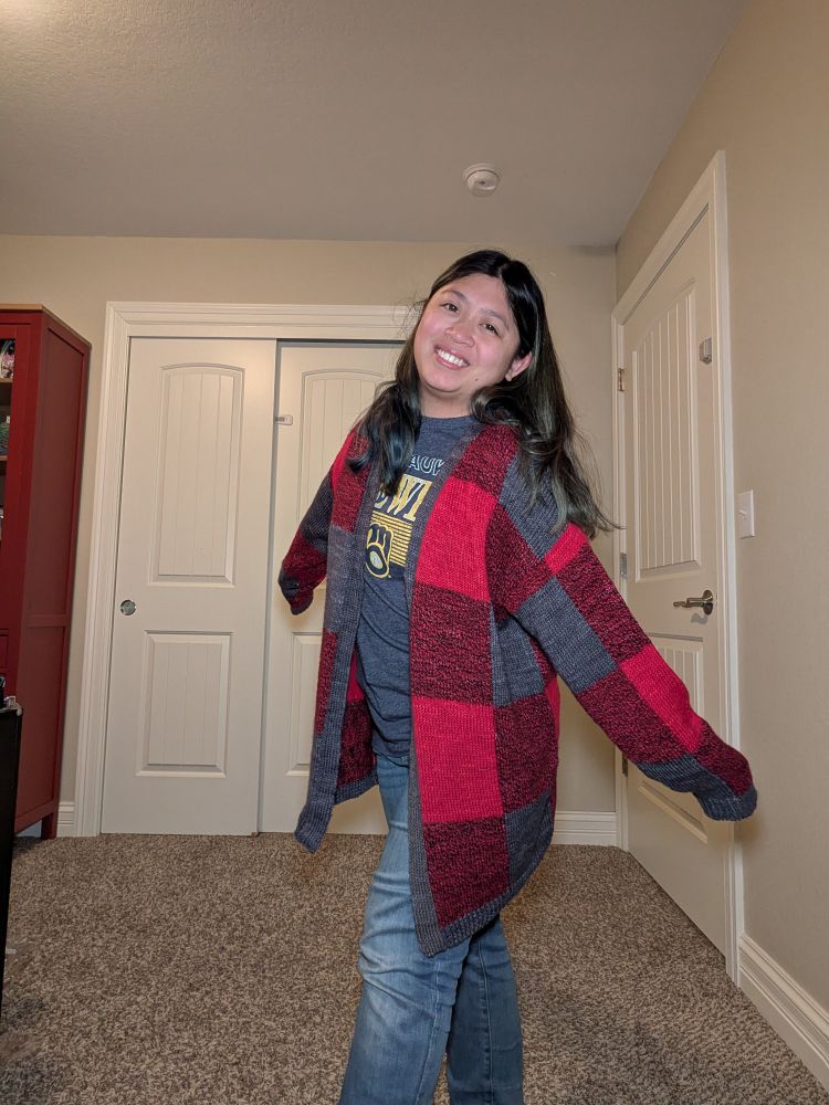 An Asian woman wearing a Caladium Cardigan, which is a plaid like pattern in red and gray