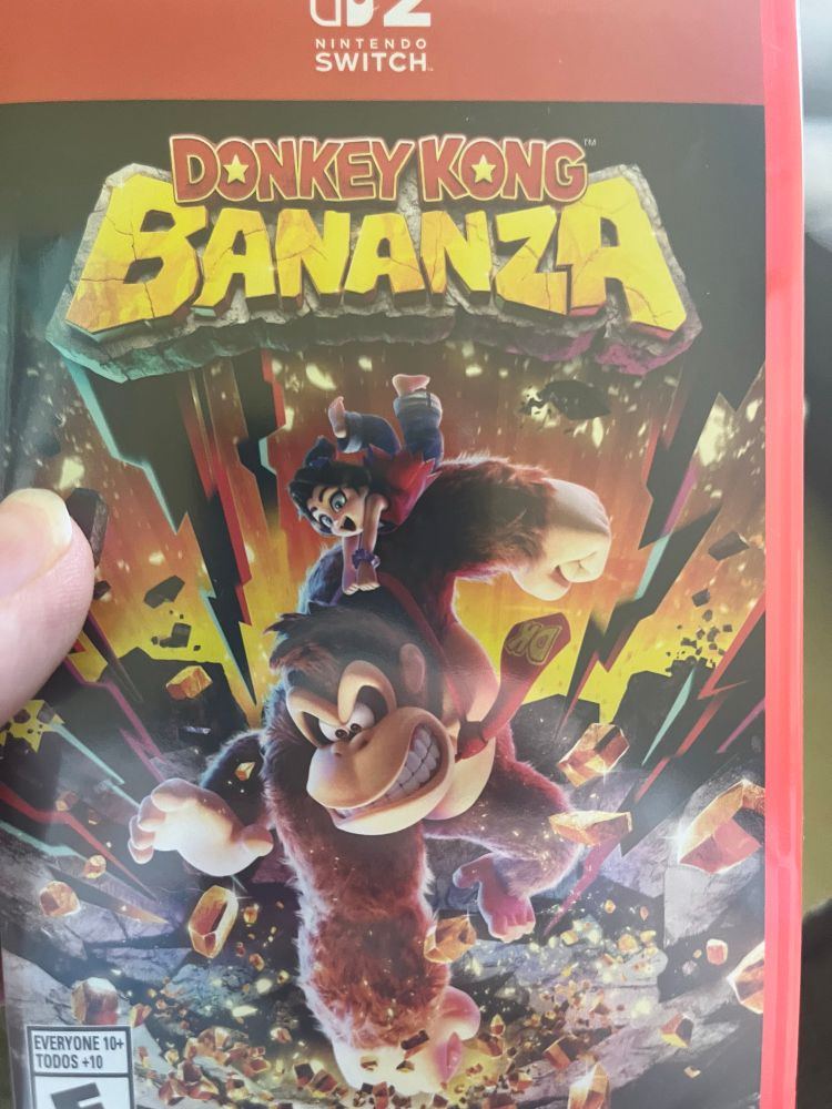 Me holding the box for “Donkey Kong Bananza”. Below the logo is artwork of Donkey Kong smashing the ground with Pauline holding onto DK’s tie.