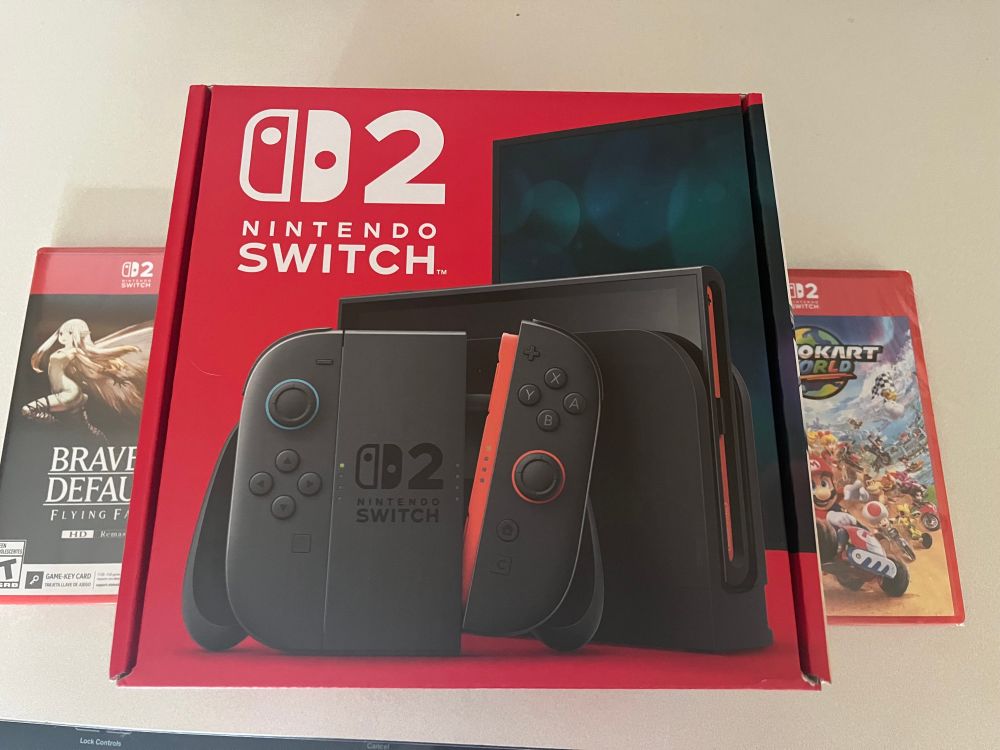 A picture of a Nintendo Switch 2 box between copies of Bravely Default (left) and Mario Kart World (right)