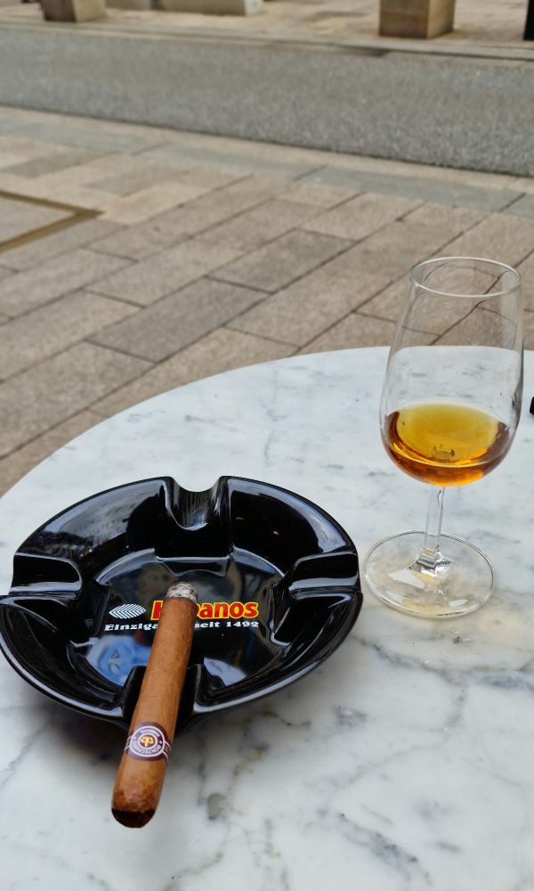 Eine Zigarre im Aschenbecher und ein Glas Rum auf einem Tisch in Hamburg.
