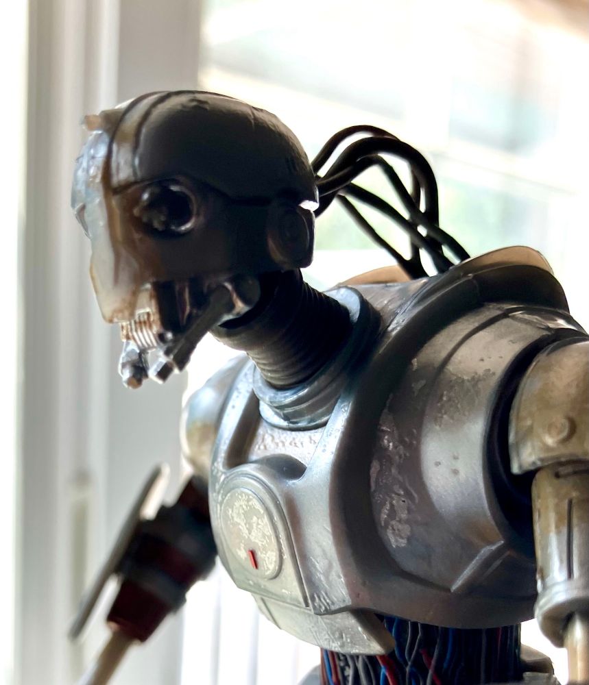 A 3/4 closeup of the head and shoulders of the droid figure showing off its wires and eye hamster.