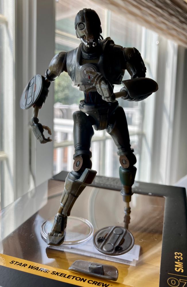 A photo of the Droid figure posed atop its box.