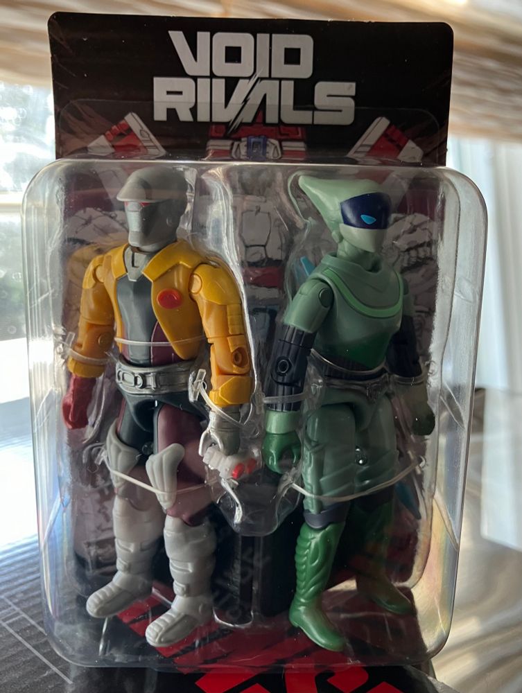 The front view of two O-Ring style action figures on a small blister card.  It has the Void Rivals logo and a drawing of Jetfire.