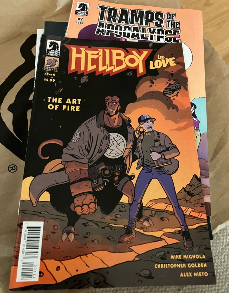 Photo of two comic books. Hellboy In Love: The Art of Fire #1 and Tramps Of The Apocalypse #2.