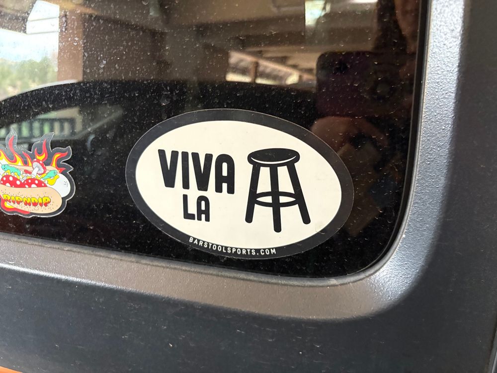 Picture of a window sticker on a car that says “viva la” and then a picture of a stool.
