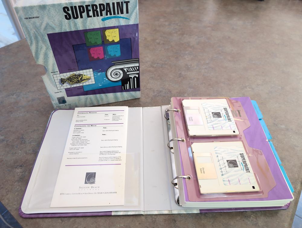 Top down angled view of the binder that's been taken out and opened at a certain page. We see that there are hundreds of pages in this binder. There's also a plastic page made to contain the 2 3.5 inch disks that it comes in. 