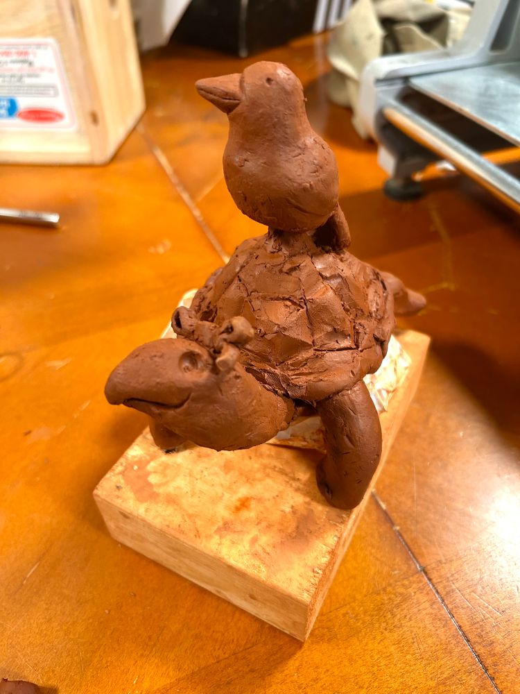 Ceramic turtle with a bow, and also a bird on her back. Pretty wet clay still 