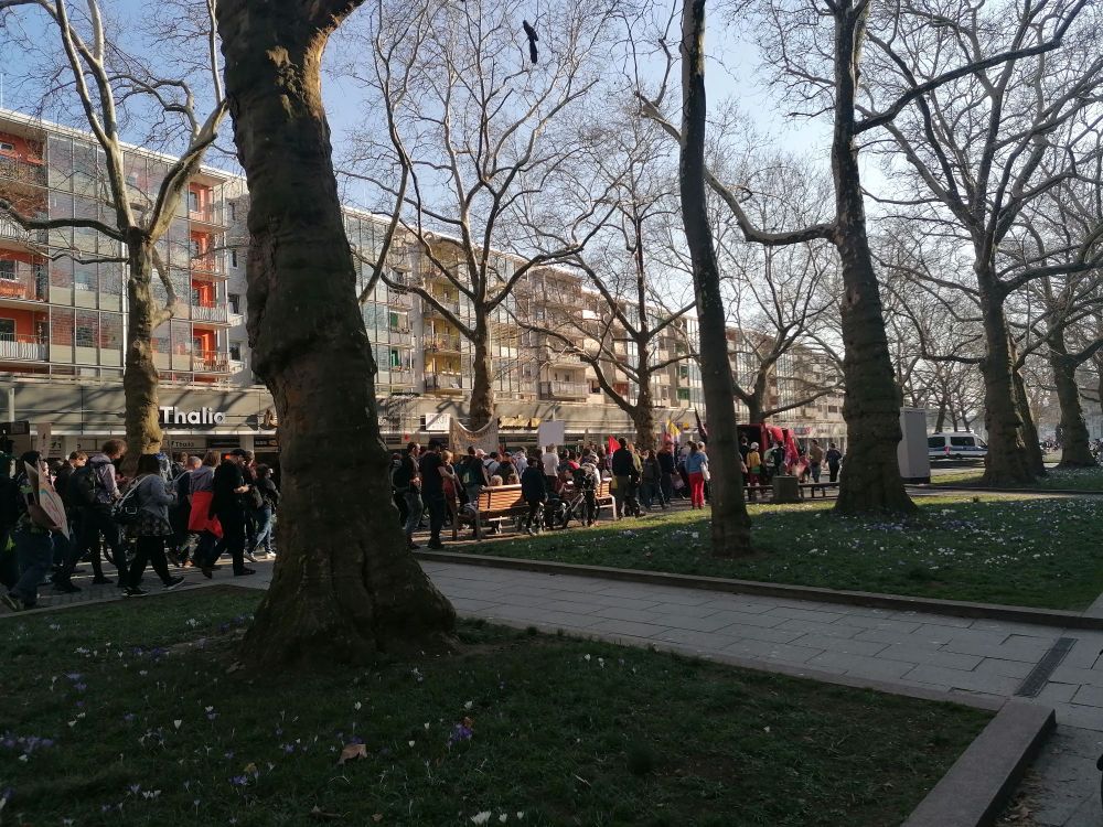 Ein Demonstrationszug läuft hinter einem Lautsprecherwagen lang. 