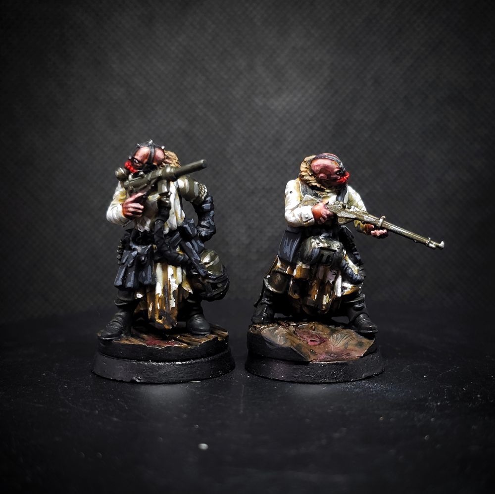 Photo of a pair of painted miniatures; Heretic Legions Troopers for Trench Crusade. Two soldiers in dirty white coats wielding guns and wearing red demonic face masks.