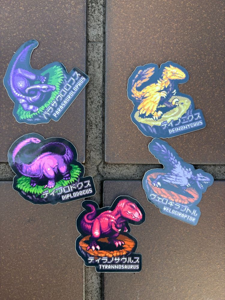 Five different dinosaur stickers, all with different monochrome pixel dinosaurs on them.