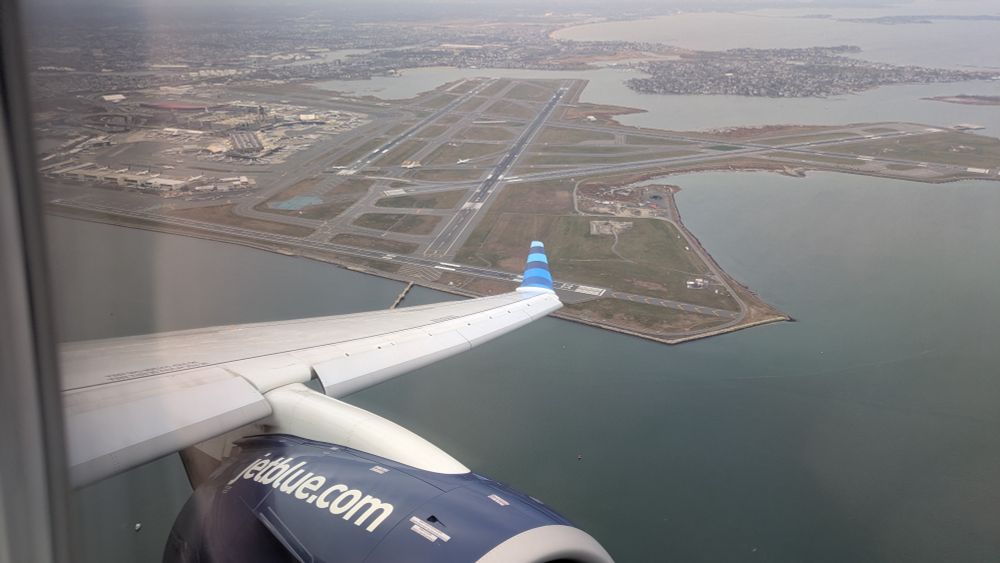 Plane wing with BOS airport in the background showing off the many runways. 