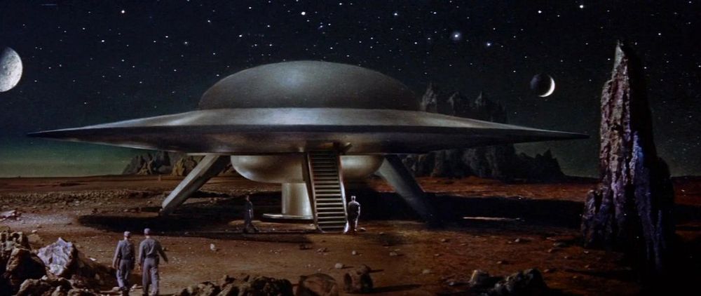 still from Forbidden Planet of 2 soldiers approaching their flying saucer on a desolate planet 