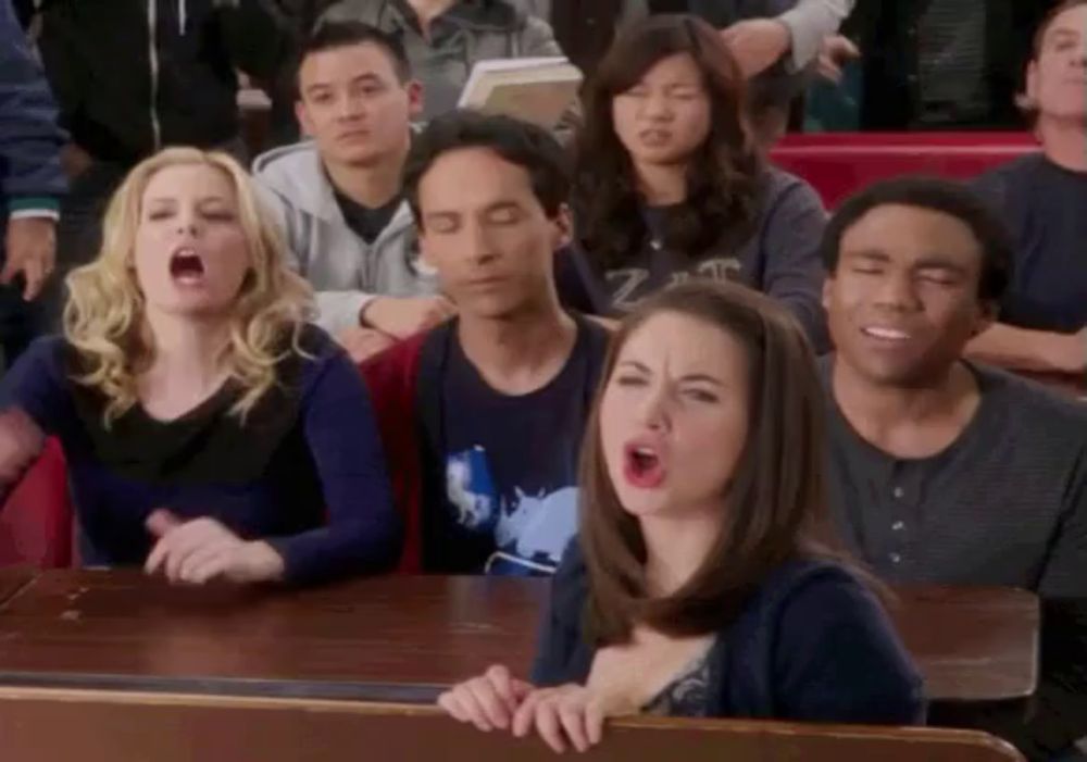 a group of people are sitting in a classroom with one woman making a face