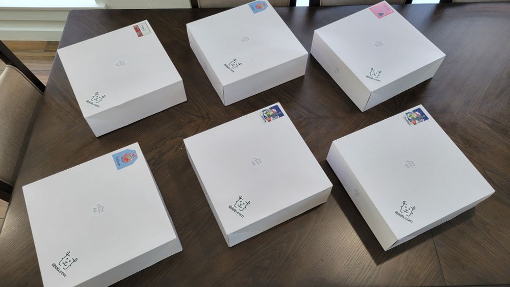 A photo of 6 white boxes on a table. They contain some goodies. Don't know what they are.