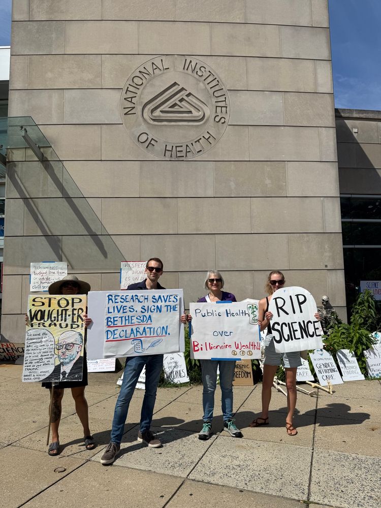 4 people holding up various protesting signs 